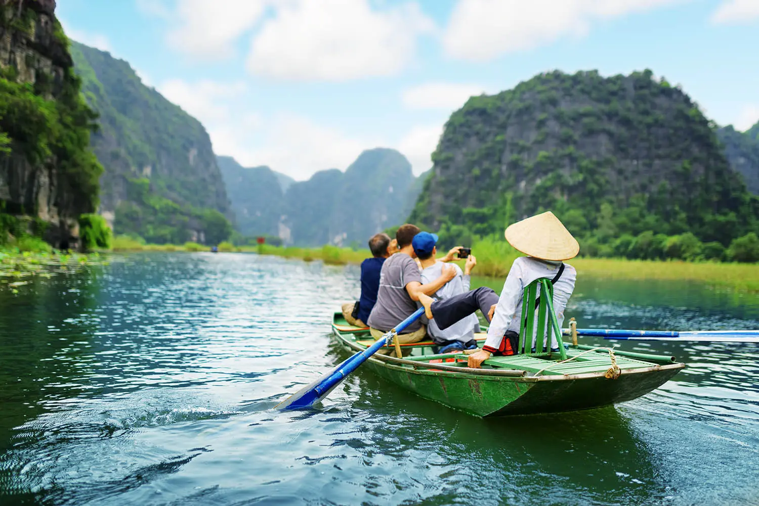 Students traveling in boat along the Ngo Dong River and taking picture of the Tam Coc, Ninh Binh, Vietnam.