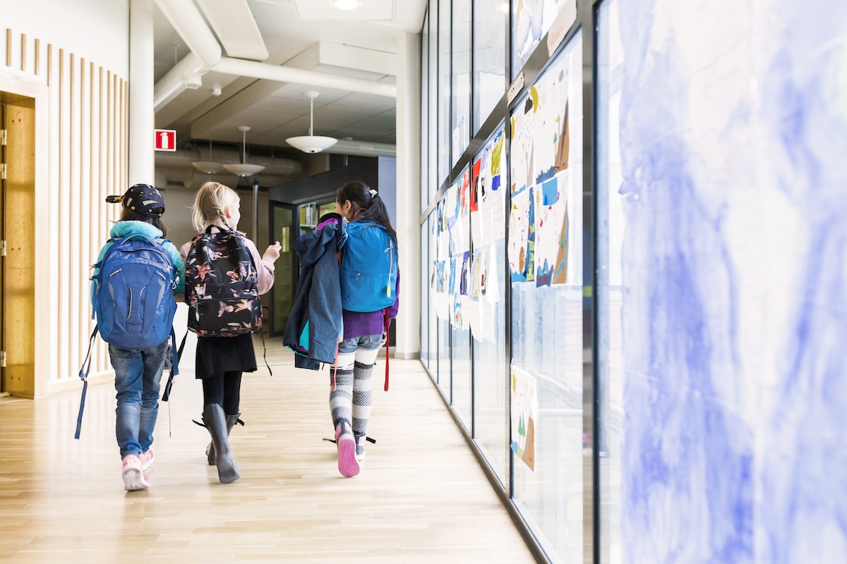 Girls (8-9) walking together through school corridor
