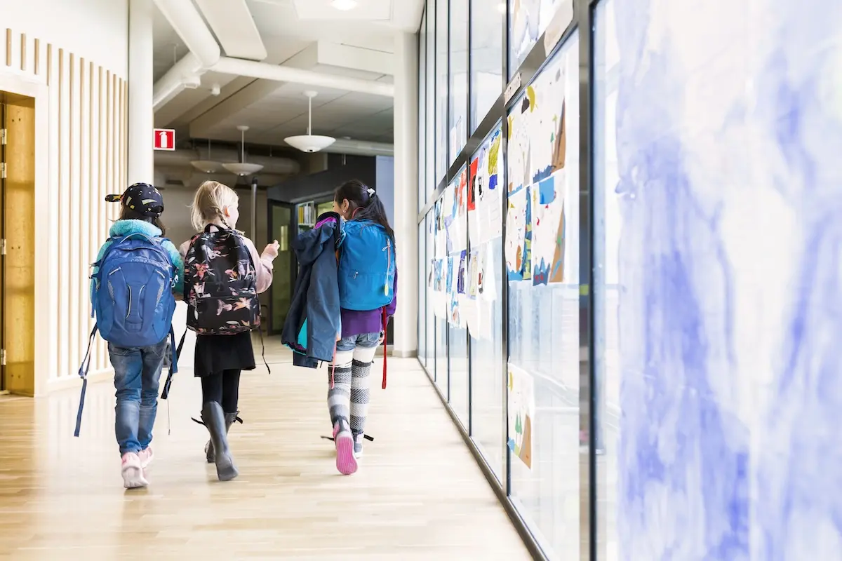 Girls (8-9) walking together through school corridor