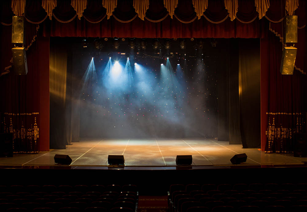 An empty stage of the theater, lit by spotlights and smoke befor