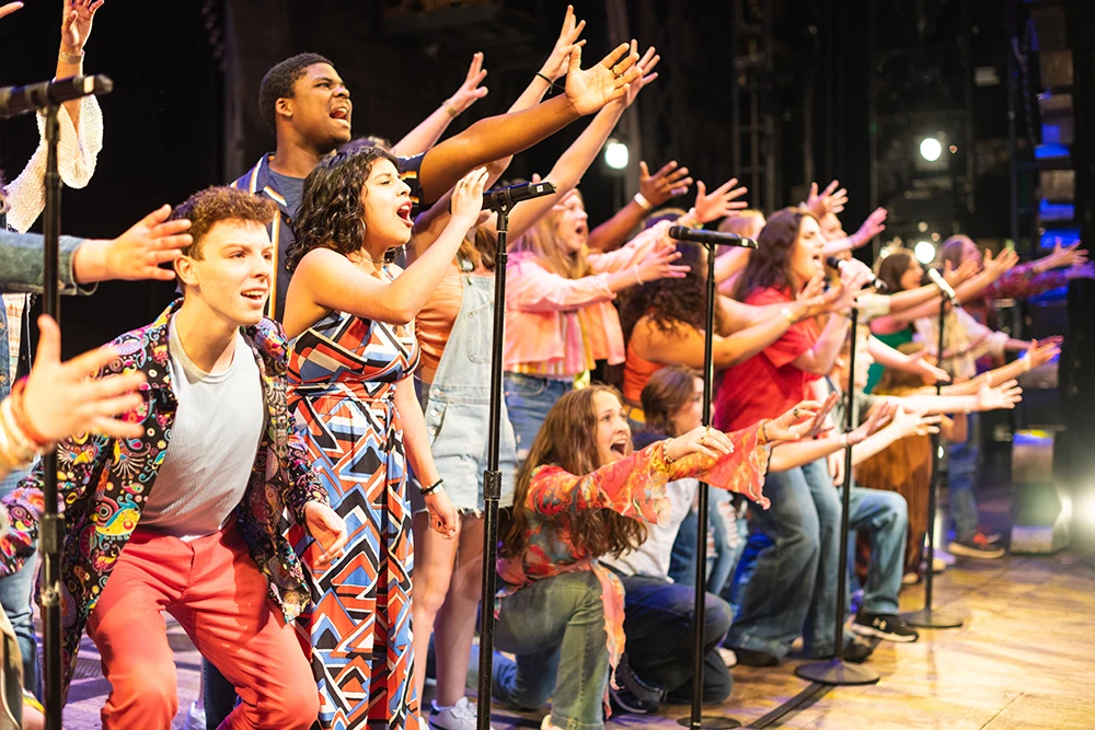 Arts for Autism singers with hands pointing toward crowd