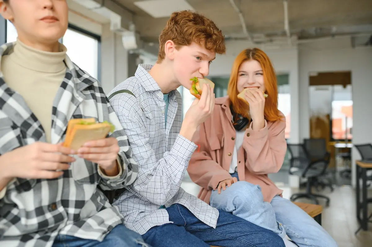 A group of young students on an educational tour eating a sandwich