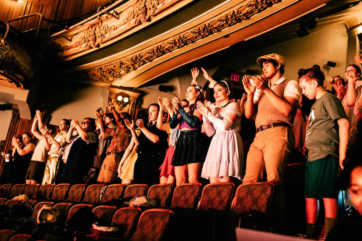 students cheering on other performers from auditorium seats
