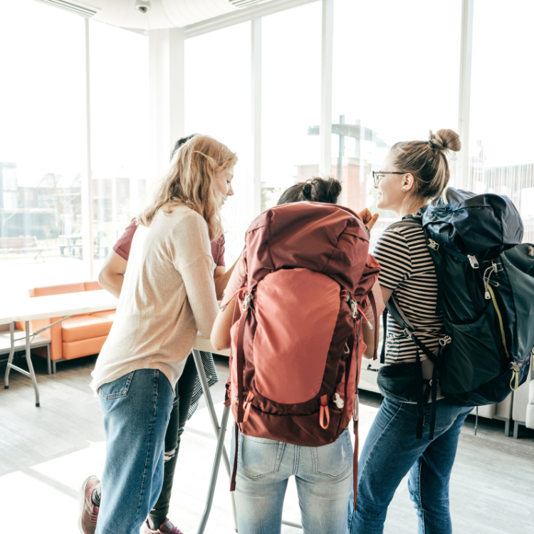 three students in an aiport wearing backpacks
